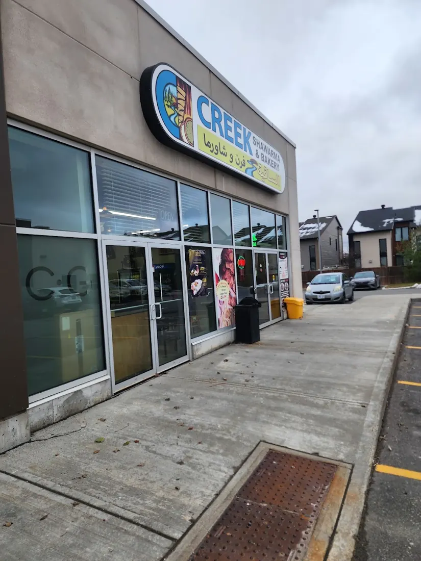The Creek storefront with the green, blue and yellow sign above glass doors