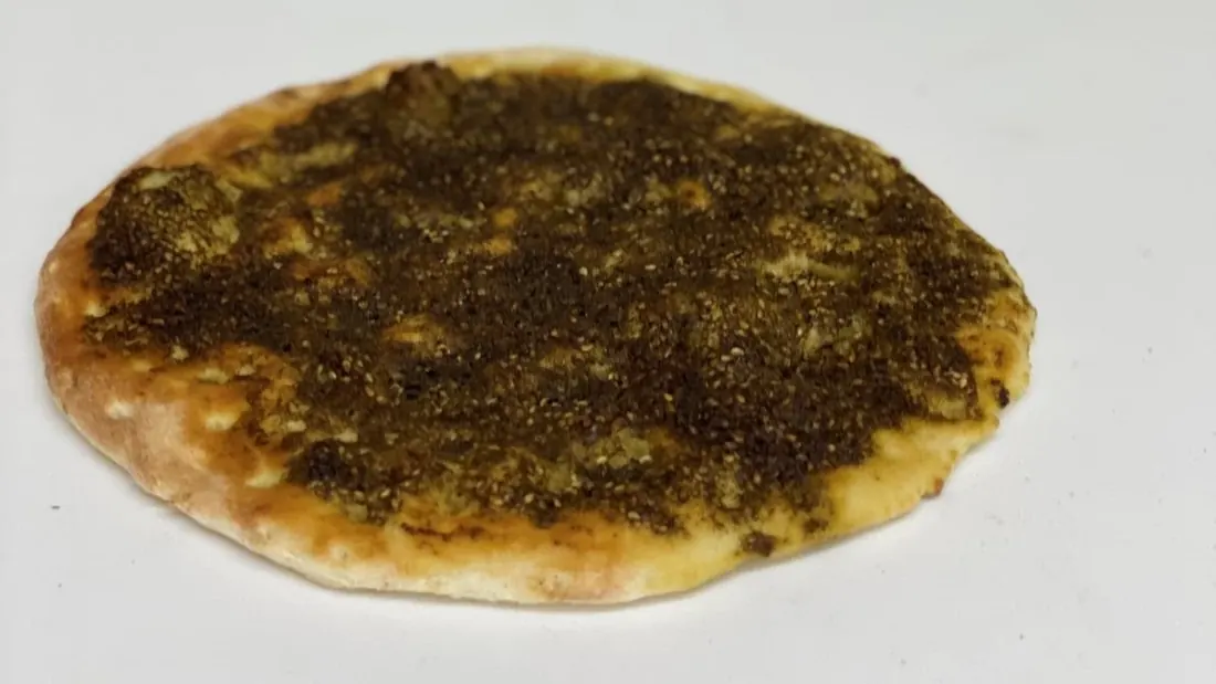 Round zaatar flatbread topped with herbs and olive oil
